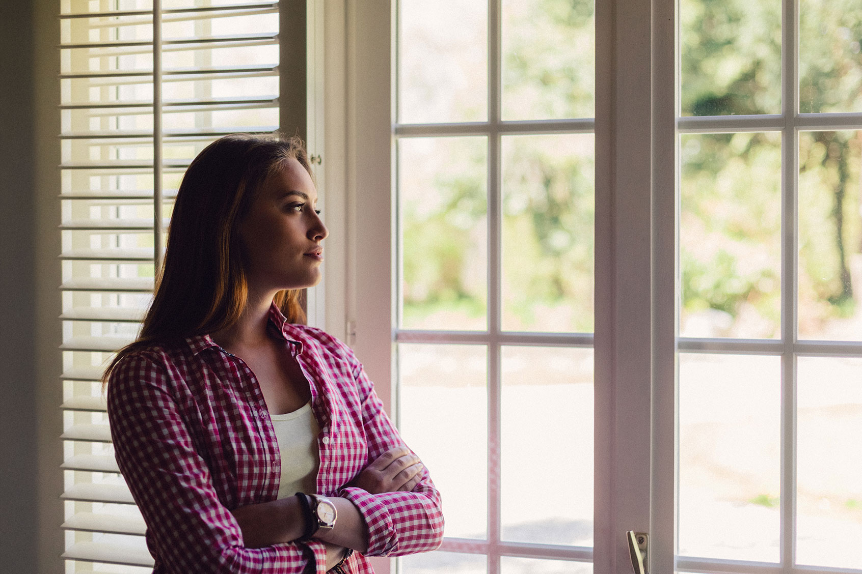 Depressed woman looking through window (Getty Images/martin-dm)