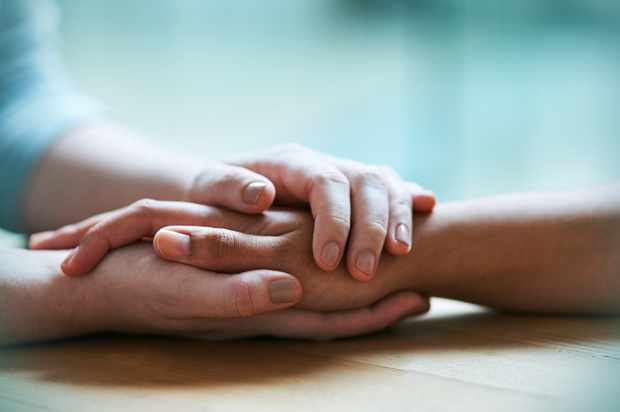 Shot of two people holding hands in comfort (Getty/PeopleImages)