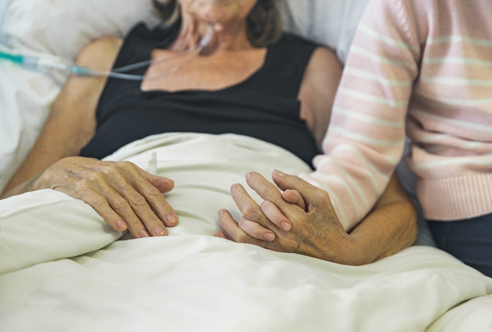 Young girl holds the hand of her ill grandmother. (Getty Images / Justin Paget)