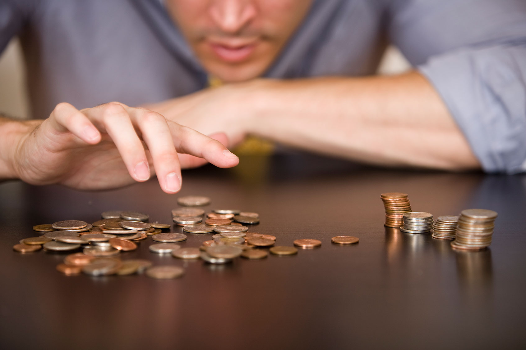 A man counts his coins on a tabletop. (Getty Images/MichaelDeLeon)