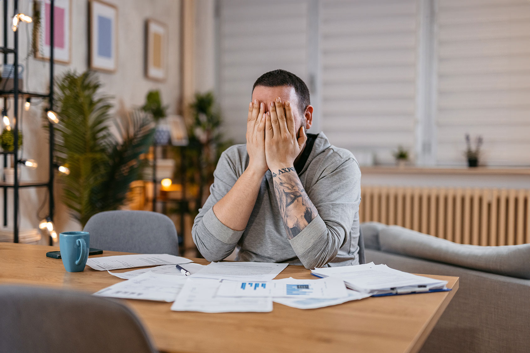 Stressed man covering his face with both hands and going through his bills and financial reports. (Getty Images/urbazon)