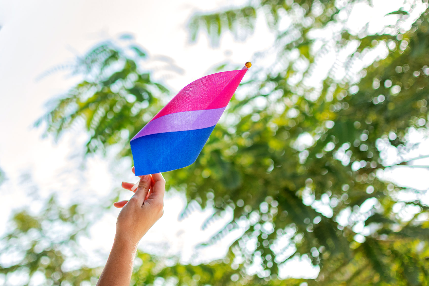 Woman holding a bisexual pride flag (Getty Images/Wirestock)